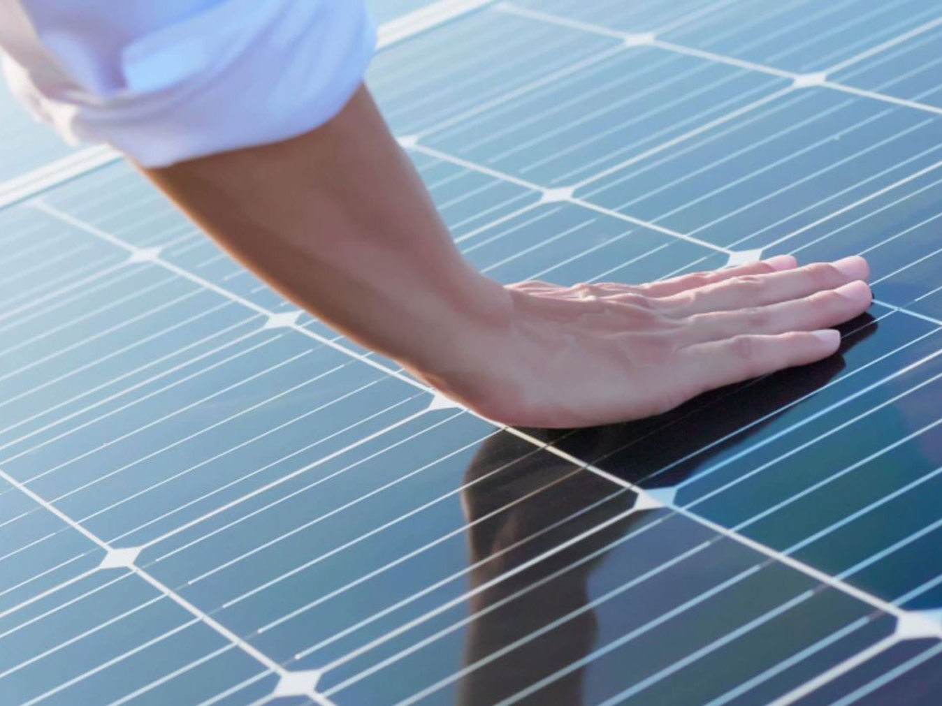 A hand touching photovoltaic modules. 