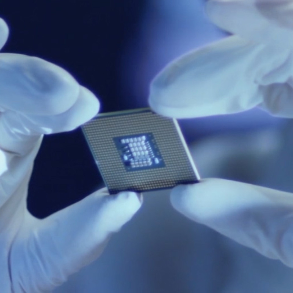 An image of a microchip held by a person with laboratory gloves. 