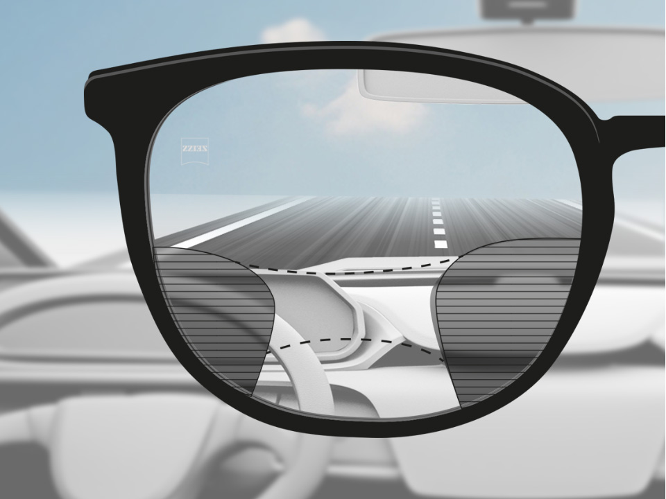 A point of view image of a driver with ZEISS Progressive DriveSafe lenses with clear vision on the street and dashboard and blurry plots on the left and right. 